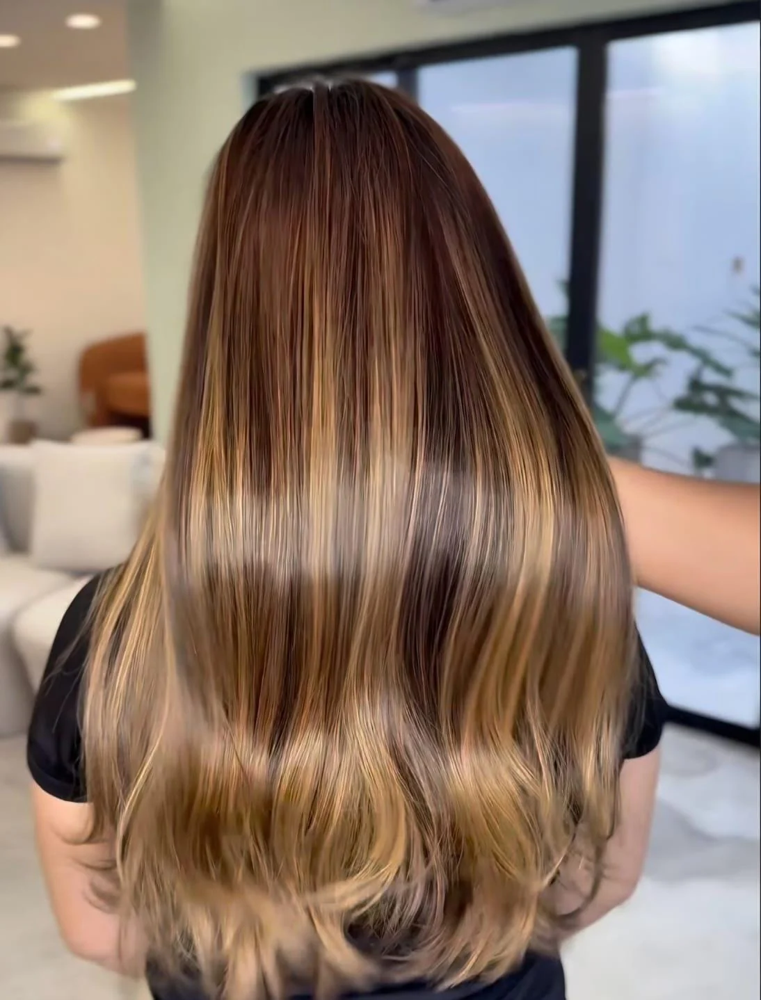 Cabelo longo com mechas iluminadas e pontas onduladas, visto de costas