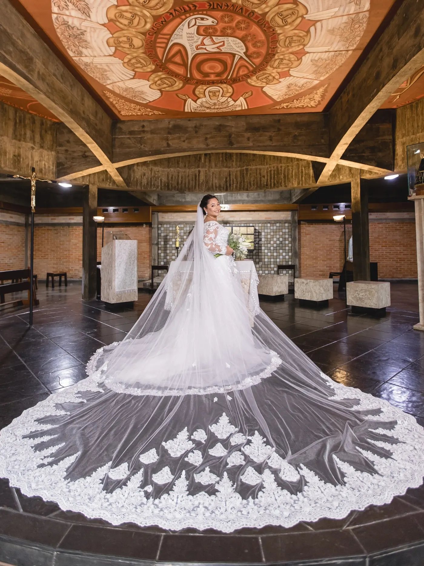 Noiva de véu longo com cauda estendida no salão da igreja