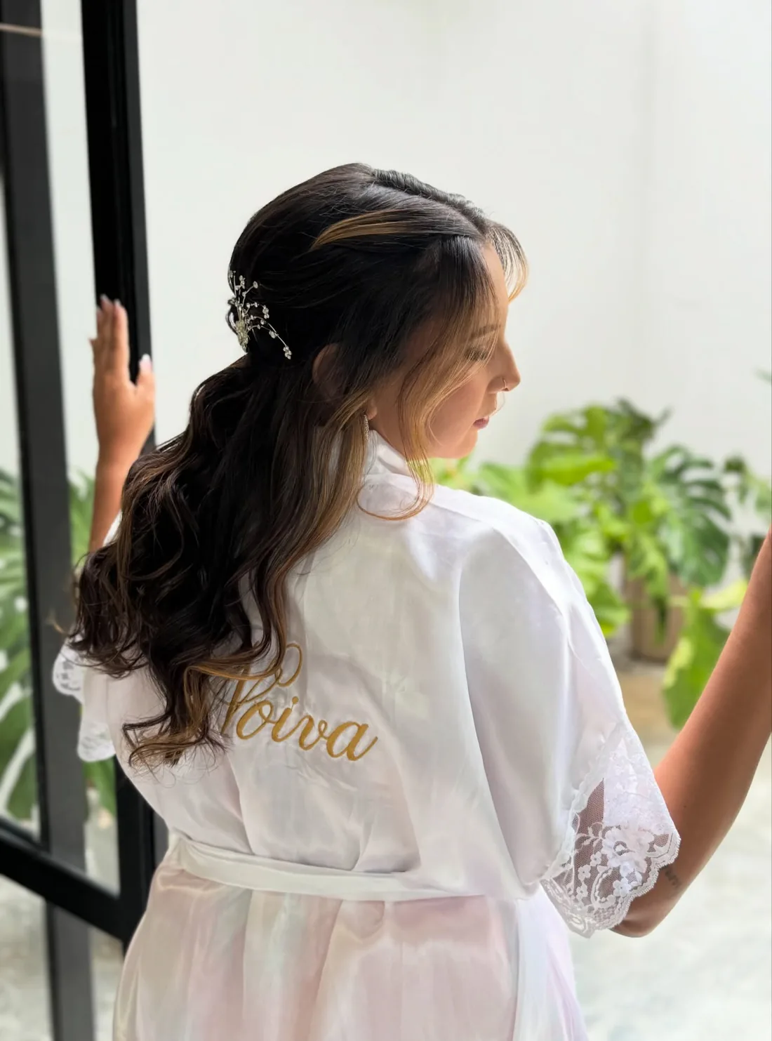 Noiva Sanmilly de robe, de costas, com penteado semipreso e enfeite de cabelo